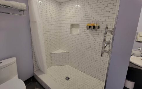 Tiled walk in shower w/hand grip, wall mounted dispensers soap, shampoo & conditioner